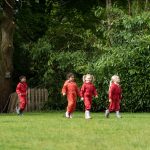 students in red jumpsuits walking along the grass